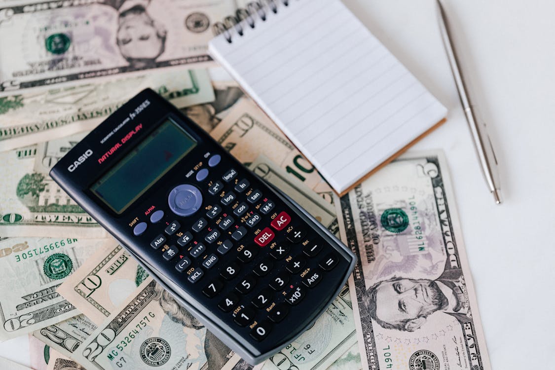 A calculator and notepad placed on U.S. dollars, representing small business financing.